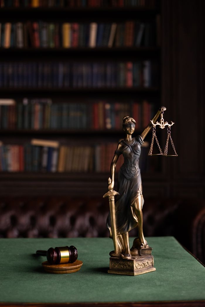Home Lady Justice and gavel on a table in a classic law library setting.